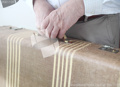 Image of Man holds old suitcase.