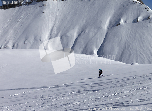Image of Snowboarder downhill on off piste slope with newly-fallen snow