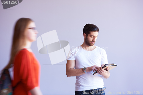 Image of student working on tablet, people group passing by