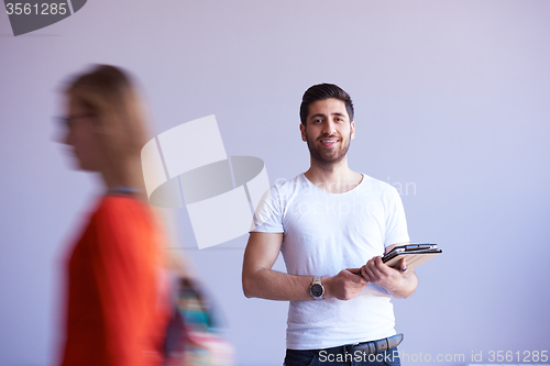 Image of student working on tablet, people group passing by