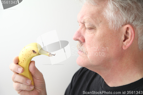 Image of Older man holds banana.