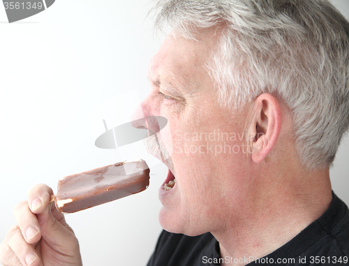 Image of Senior man with ice cream bar profile view