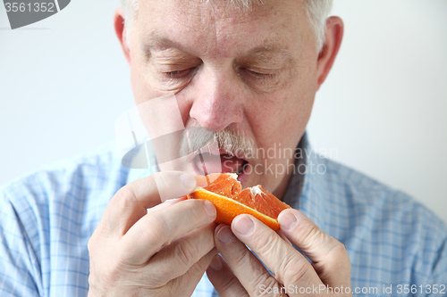 Image of Older man eating orange