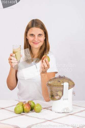 Image of Girl holding freshly made juice in one hand and a pear in another