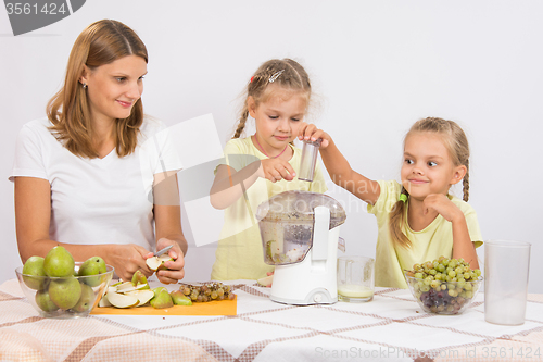 Image of Children throw the fruit in a juicer in the care of mothers