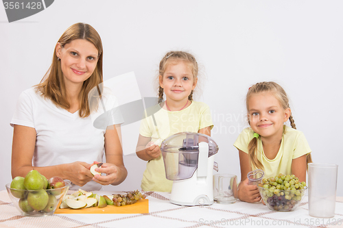 Image of Mom and daughter sit at the table and cut fruit for juicing