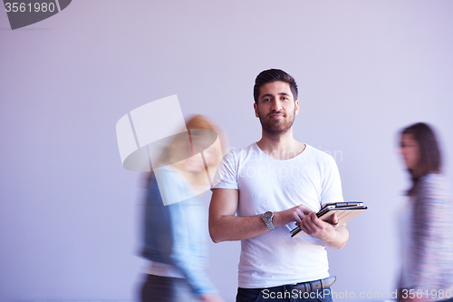 Image of student working on tablet, people group passing by