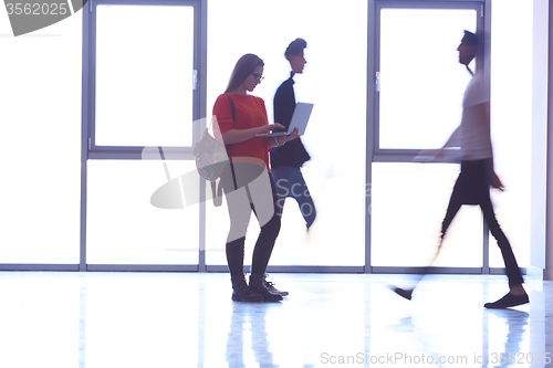 Image of student girl standing with laptop, people group passing by