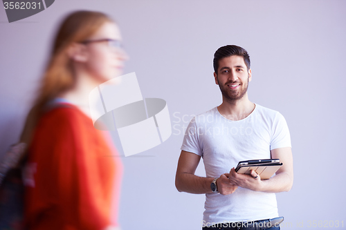 Image of student working on tablet, people group passing by