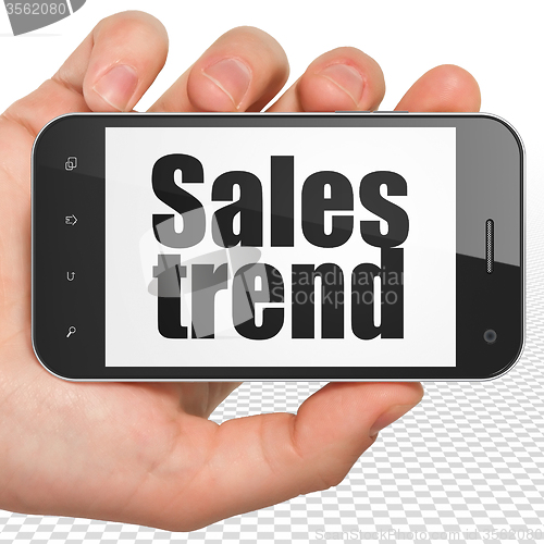 Image of Advertising concept: Hand Holding Smartphone with Sales Trend on display