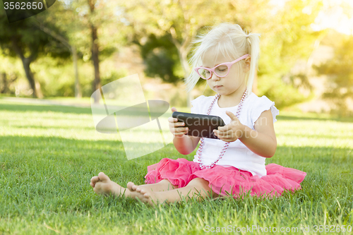 Image of Little Girl In Grass Playing With Cell Phone