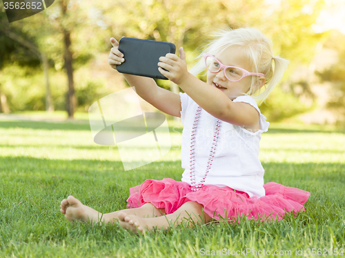 Image of Little Girl In Grass Taking Selfie With Cell Phone