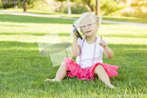 Image of Little Girl In Grass Talking on Cell Phone