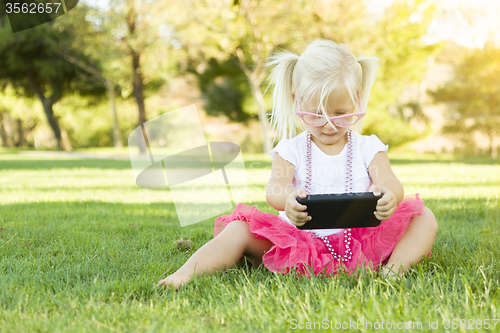 Image of Little Girl In Grass Playing With Cell Phone