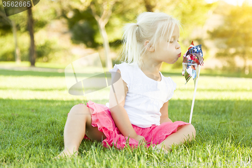 Image of Little Girl In Grass Blowing On Pinwheel