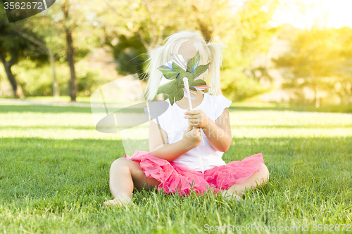 Image of Little Girl In Grass Blowing On Pinwheel