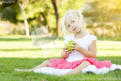Image of Little Girl In Grass Eating Healthy Apple