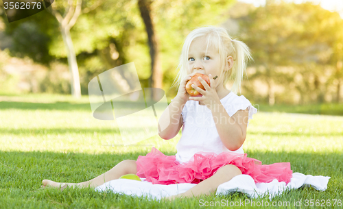 Image of Little Girl In Grass Eating Healthy Apple
