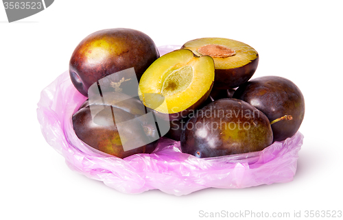 Image of Whole and half violet plums in plastic bag