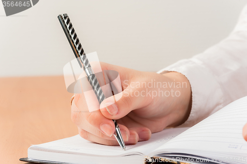 Image of Business woman writing in notebook
