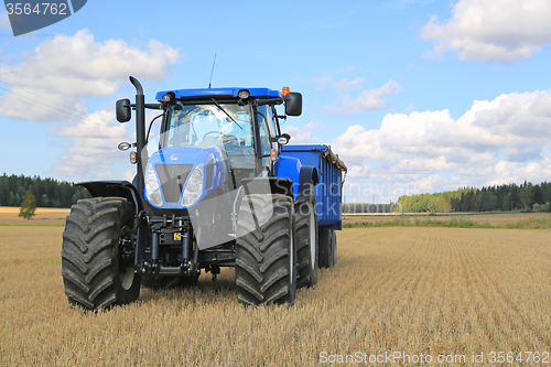 Image of New Holland Tractor and Agricultural Trailer on Field in Autumn
