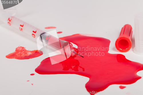 Image of Syringe Squirting Red Blood onto White Background