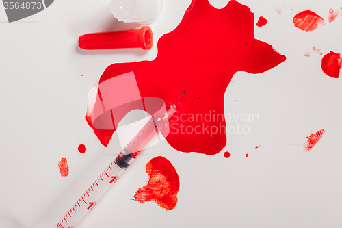 Image of Syringe Squirting Red Blood onto White Background