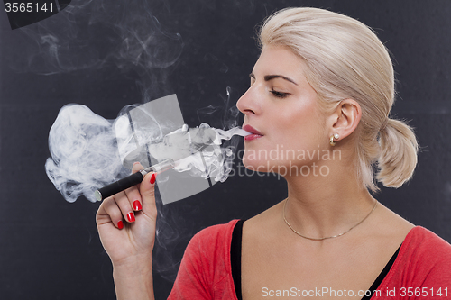 Image of Stylish blond woman smoking an e-cigarette