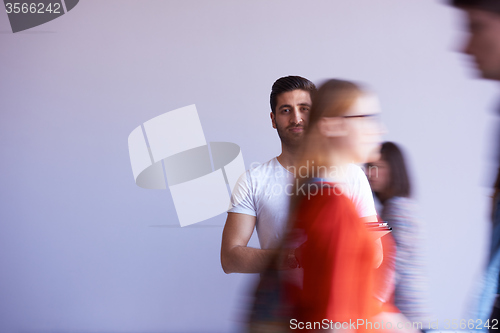 Image of student working on tablet, people group passing by