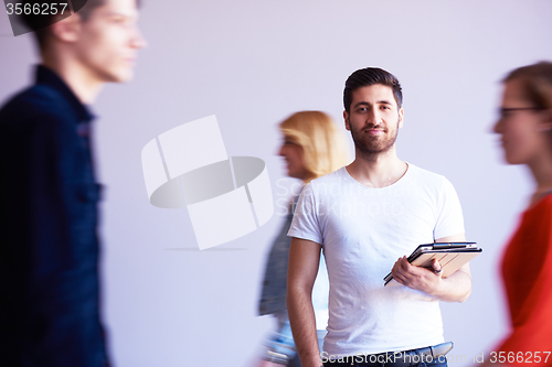 Image of student working on tablet, people group passing by