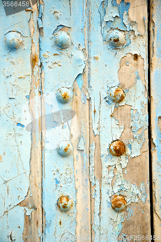 Image of dirty stripped paint in the blue wood door   rusty nail