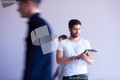 Image of student working on tablet, people group passing by