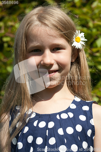 Image of young girl with camomile flower in the hair