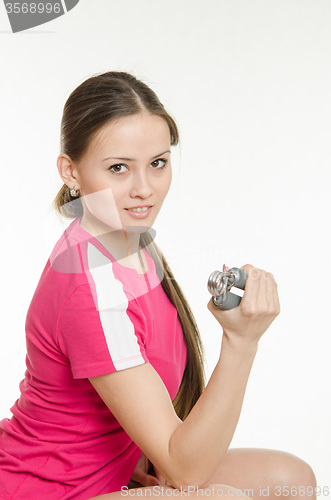 Image of Sportswoman sitting and flexing arm muscles expanders