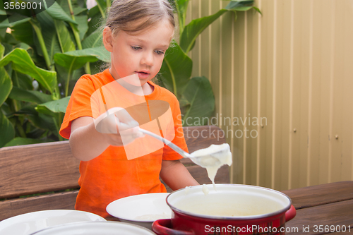 Image of Girl at breakfast porridge scoop ladle