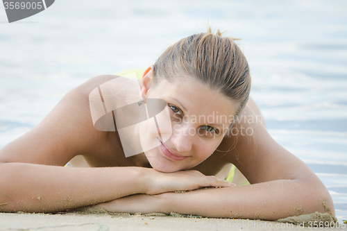 Image of Happy girl on the riverbank lies