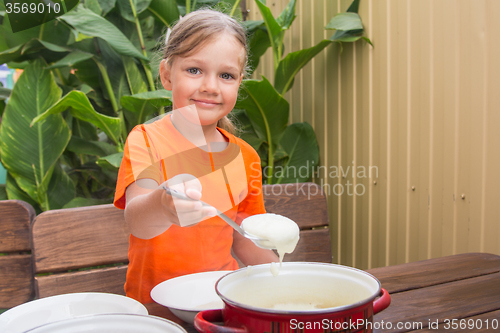 Image of Girl with a smile imposes semolina his plate