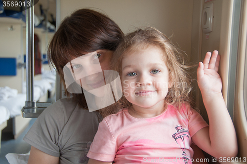 Image of Young girl with a baby sitting on the side a place in the second-class train carriage