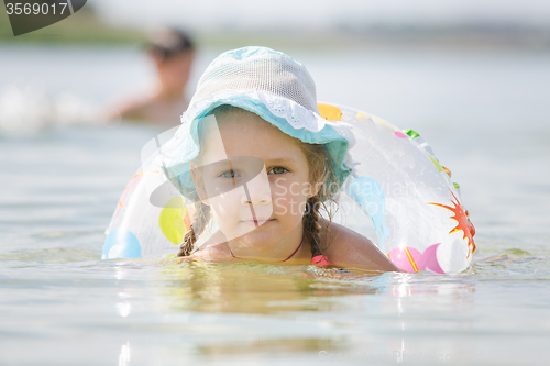 Image of Concentrated four-year girl with a circle floating in the river