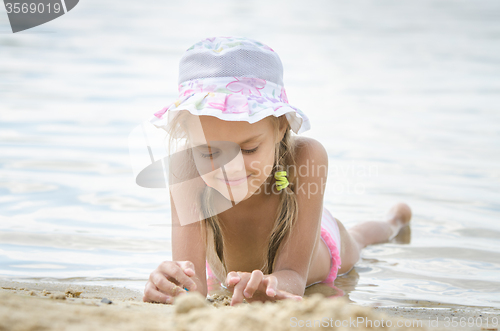 Image of The girl in panama lying on the sand by the river