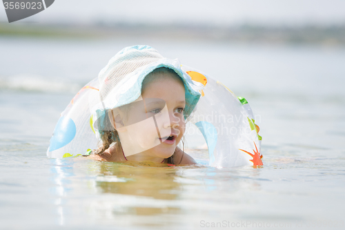 Image of Four-year girl with a circle floating in the river