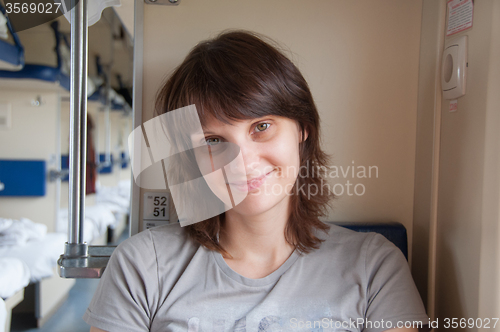 Image of Young girl sitting on the side in place of second-class train carriage