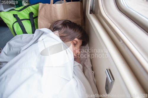 Image of Young girl asleep in a second-class train carriage