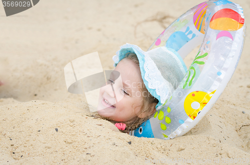 Image of The girl was buried in the sand on the beach and put it under his head round