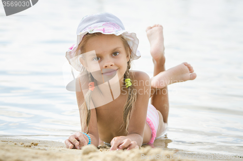 Image of Six year old girl lying on the sand on the beach