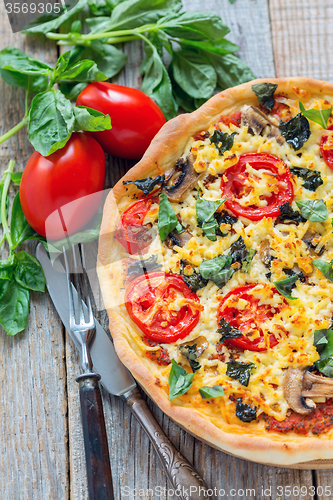 Image of Pizza with mushrooms, tomatoes and basil.