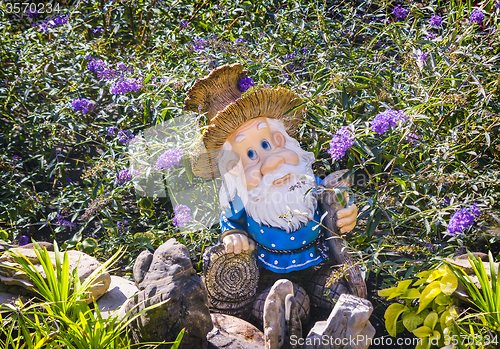 Image of Interesting statue of a dwarf among the flowers.