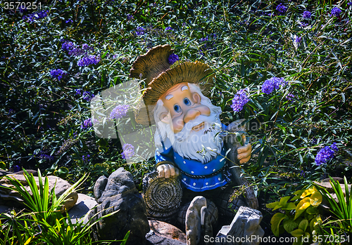 Image of Interesting statue of a dwarf among the flowers.
