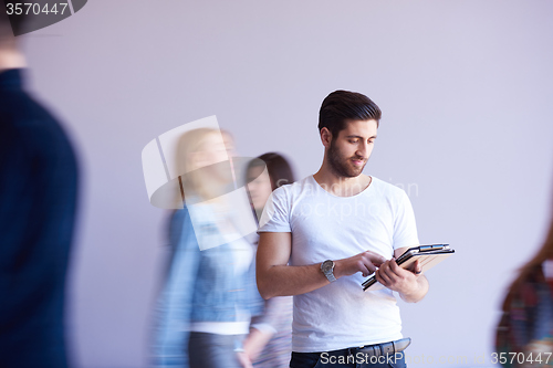 Image of student working on tablet, people group passing by