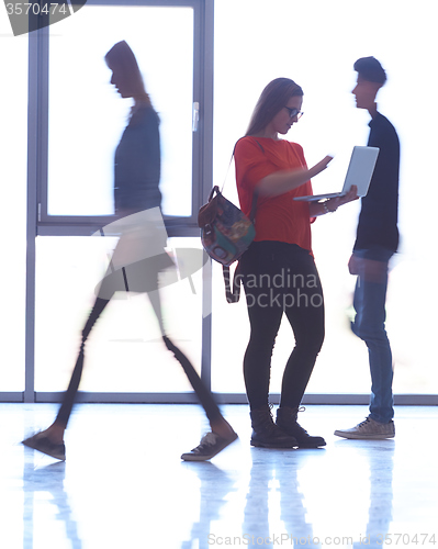 Image of student girl standing with laptop, people group passing by